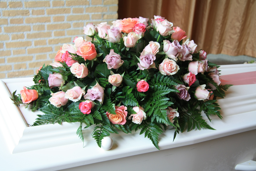 White coffin with pink sympathy flowers