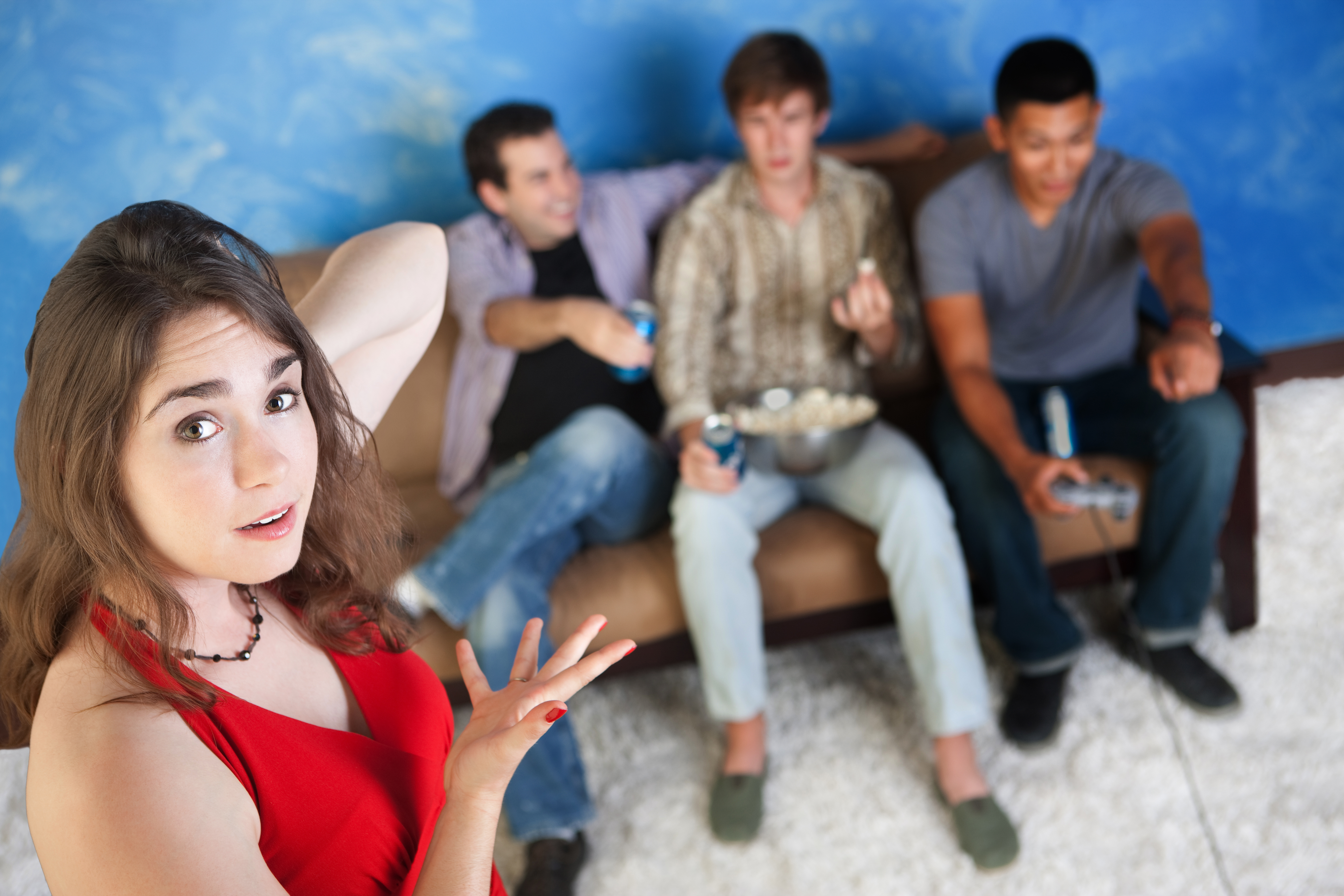 Annoyed young Caucasian woman with three men playing video games