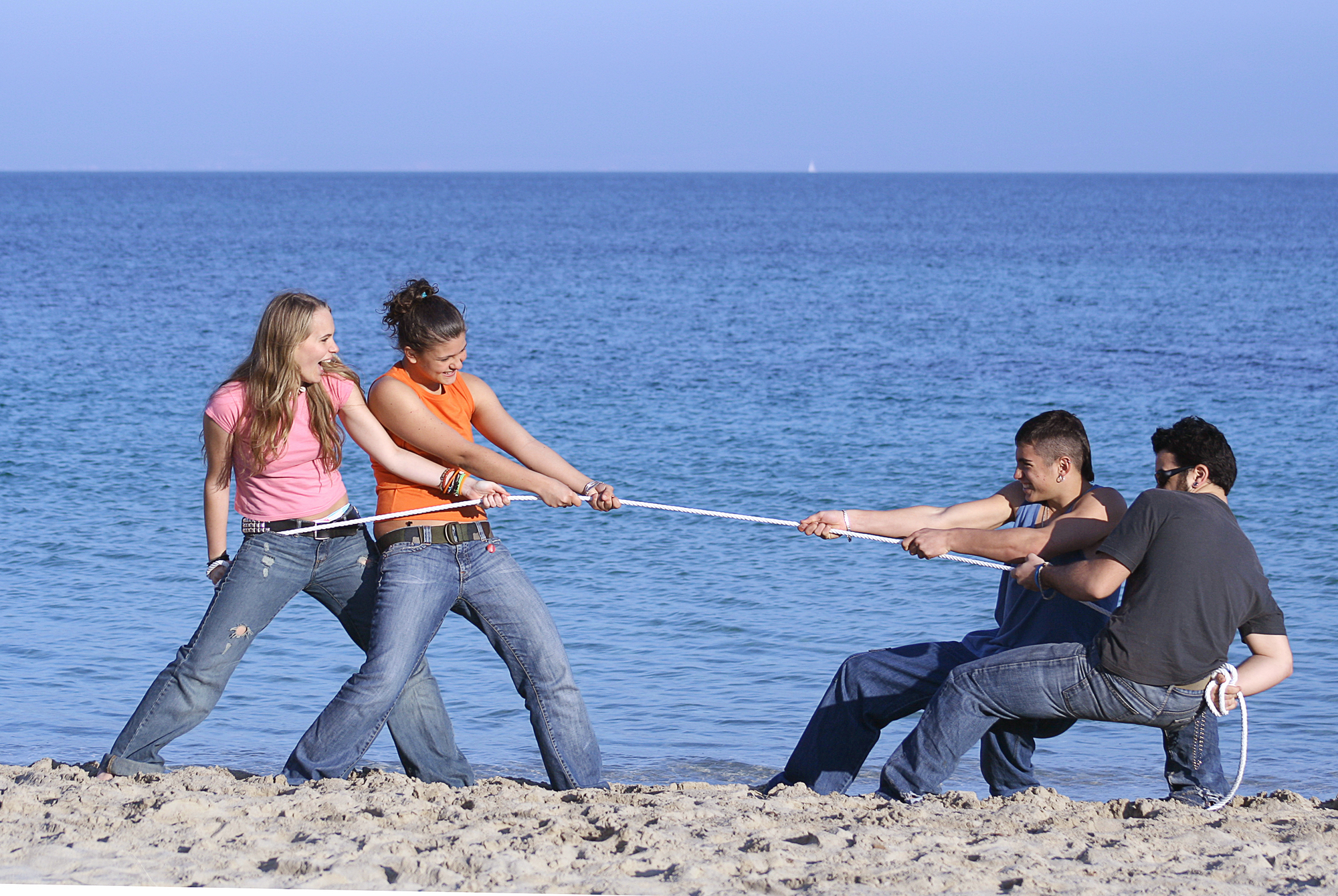 tug of war, teens playing on beach on summer vacation or spring break